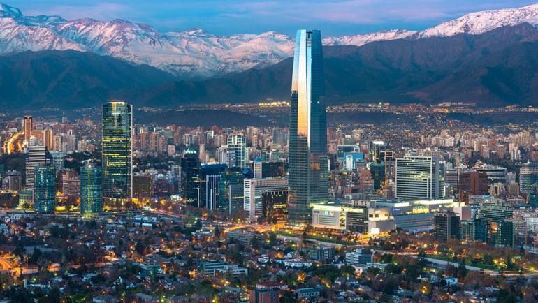 Vista de Santiago no inverno com cordilheira nevada e vinhedos ao pôr do sol